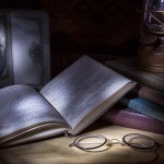A book, an old black and white photo, reading glasses, a stack of books and a lantern light painting